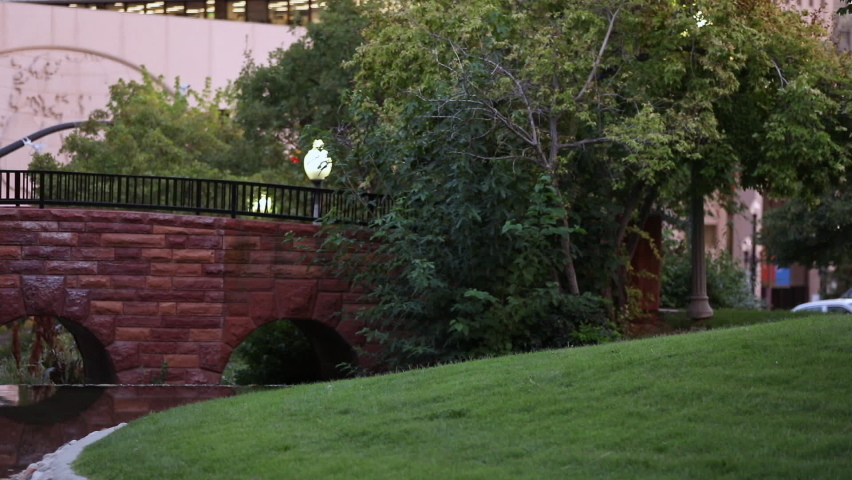 Panning view of man jogging over bridge in park through Salt Lake City.