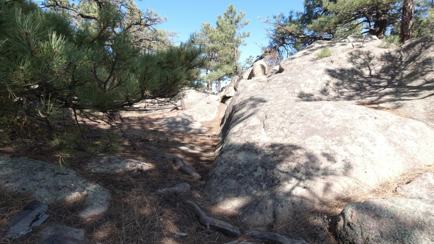 Hiking a path on a sunny fall afternoon around large boulders