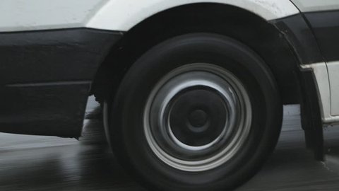 Car wheel on the road in heavy rain moving fast close up