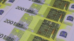 Colorful paper clips fall on the table laid out 200 euros banknotes