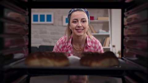 Beautiful blonde-haired woman takes out a delicious Turkish bagel from the oven. Shooting through the oven. 