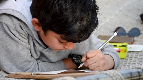 Portrait of Indian school kid wring on page with pencil