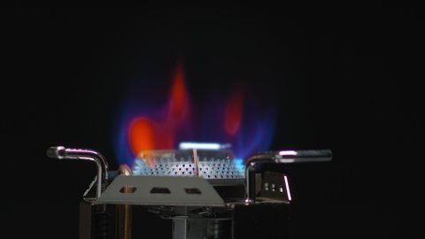 Gas stove being turned on in the dark background, Close up of gas is switching on, apearing blue end red flame.