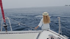 The bottlenose dolphins swim and play with the bow of the tourist boat. Woman standing near railing on yacht catamaran, enjoy sea view during cruise. Girl taking video on phone