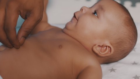 Close up black father tickling tummy of his newborn baby . Fatherhood and multiracial family. High quality 4k footage