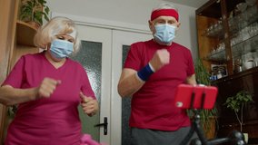 Retired senior couple doing workout, training, fitness, sport activity exercises at home. Elderly grandmother grandfather making live stream, vlog, blog, online distance course during coronavirus