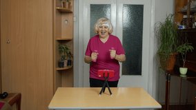 Mature woman fitness trainer coach recording video online workout course with a smartphone live streaming sport exercises at home. Senior grandmother live stream blog, vlog during coronavirus lockdown