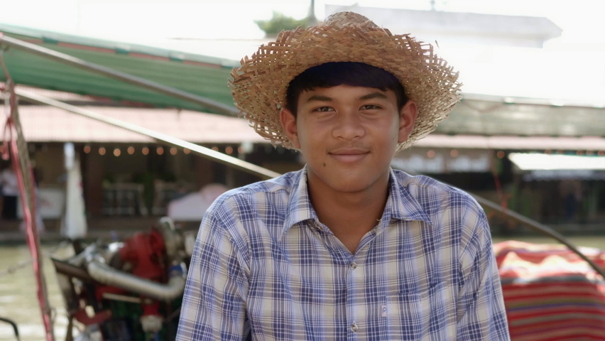 Tourist boat driver, smiling young Thai farmer, earning extra income on vacation, hiring tourists on a beautiful canal in Thailand.