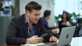 businessman sitting in coffee shop talking with earphone using laptop computer and smartphone Communicate to Customer or client by internet . discussion and consult online