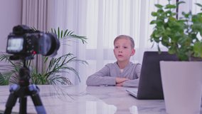 White boy speaks in front of a video camera for his blog channel. Child blogger videotapes his vlog at home. Boy recording his video blog.  Little 8 year vlogger makes online streaming using phone