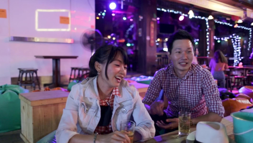 Asia friends partying girls in a nightclub and toasting drinks. Happy young asia people with cocktails at street pub
