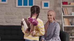 Happy Mother's Day! The little girl congratulates her mother in a hijab and gives a flower. The mother and daughter are smiling and hugging. Family vacation and togetherness. - Powered by Shutterstock - Get 15% off with code: PIKWIZARD15
