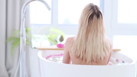 Beautiful Sexy Caucasian Blonde Girl In Bikini Lying In Flower Bath In Resort Day Spa Salon. Skin Care Therapy. Concept young woman relaxing in the bathtube. Slow motion video. stock footage