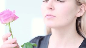 Beautiful young woman with delicate rose flower. Girl clean fresh skin touching her face in flowers. Slow motion video. stock footage