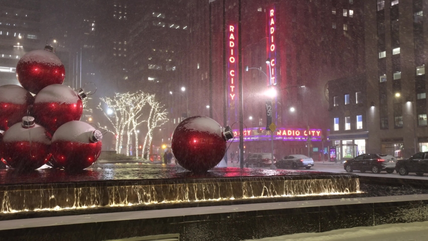New York, NY - December 16 20202: A snowstorm in midtown Manhattan by the Radio City Music Hall with the red Christmas decorative balls in the pool