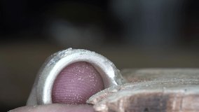 Jeweler smoothing a silver ring he creates. Close up.