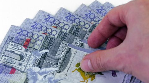 Man’s hand counting Kazakhstani 20.000 tenge banknotes on white surface. Savings and financial  success concept