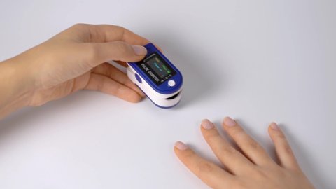 Close-up on a finger, putting on a pulse oximeter to check the pulse of the amount of oxygen in the blood. White background. Diagnosis of a patient by a doctor.