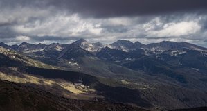 Cinematic time-lapse of rocky peaks almost touching the stormy clouds during a rainy, cloudy summer day with the gentle movement of solid shadows. 