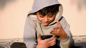 Portrait of Indian happy kid wearing stylish hoodie and talking on videocall with vivid expression