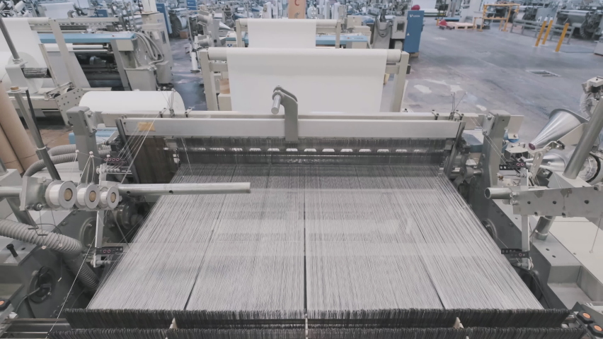 glass fiber production at the factory, macro fiberglass stretches through holes at plant. closeup large loom weaves white synthetic fiber Royalty-Free Stock Footage #1064374228