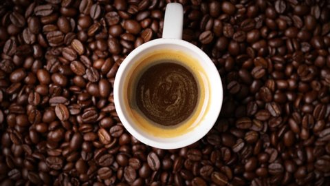 cup of coffee with fresh roasted coffee beans background (seamless looping)