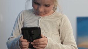 Cute little girl looking and playing with smartphone.