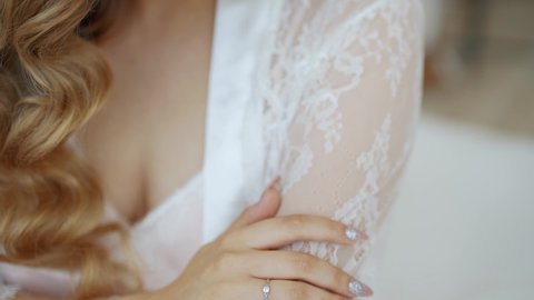 Close-up, a young woman stroking herself with a hand with a manicure and a ring on a white lace negligee