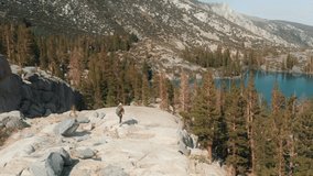 Woman in outdoor nature. Brave and fearless female traveler exploring wild nature in Sierra Nevada mountains. Drone flying around the person above scenic rocks and pine tree forest on summer day 4K - Powered by Shutterstock - Get 15% off with code: PIKWIZARD15