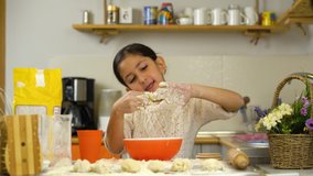 Kid girl cooking in kitchen. Little girl learn cooking in quarantine time. Covid -19 virus. Little girl play with dough in kitchen. Alone at home. High quality 4k footage. Preparing cake.