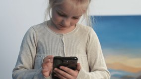 Cute little girl looking and playing with smartphone.