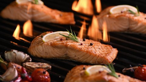 Grilled salmon fish with various vegetables on the flaming grill