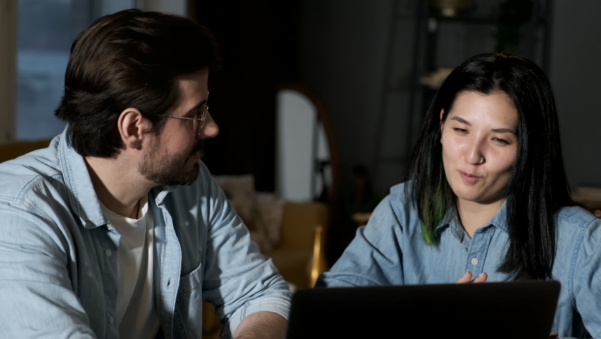 Close up portrait young couple sitting in front of a notebook at home. Handsome brunette man and cute woman working at laptop.