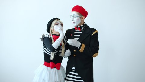 Cute mimes man and woman are eating and sharing imaginary meals then smiling hugging expressing love standing on white background. People and relationship concept.