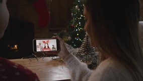 Over the Shoulder Shot of Couple Talking to Friend On Phone Christmas Video Call