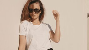 Female dressed in summer hipster clothes. She posing on the street background near wall. Funny and positive woman having fun in sunglasses
