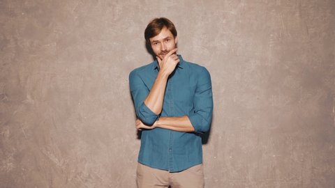 Portrait of handsome smiling hipster lumbersexual businessman model wearing casual jeans shirt clothes. Fashion stylish man posing against gray wall in studio. Crossed arms