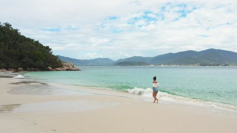 Beautiful girl walking along the beach, aerial footage from Florianópolis Santa Catarina Brazil