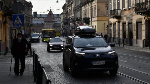European town street time lapse. Busy car traffic and people walking by crosswalk over cobblestone road of ancient architecture cityscape. Yellow bus and tram transportation. Lviv, Ukraine 10 09 2020
