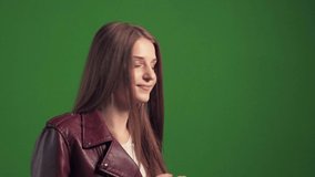 The girl looks to the side so that no one can see and sends an air kiss to the camera. Human emotions love. Green background.