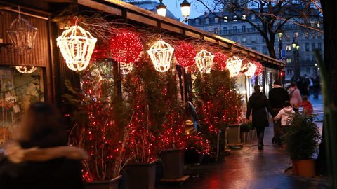 people walk at stalls with Christmas trees decorated lighted lanterns and illuminated in Paris evening Stock Video
