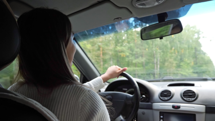Young businesswoman drives new car and shakes hand dancing and singing against forestry landscape outside window on sunny day close cabin view | Shutterstock HD Video #1064455816