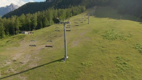 AERIAL: Flying along an empty chairlift of a ski resort in Slovenia not working the summer off-season. Ski lift is stalled during the summertime for maintenance. Drone shot of Kranjska Gora resort.