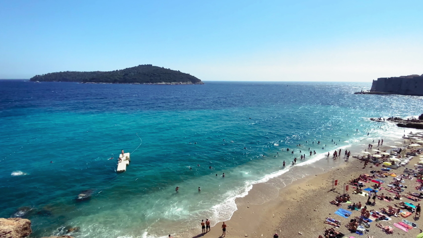 Banje Beach Dubrovnik is a beautiful aerial pan right view of swimmers at Banje Beach, Dubrovnik, Croatia. | Shutterstock HD Video #1064471554