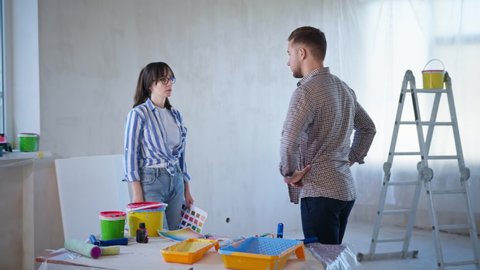 quarrel and reconciliation, man and woman yell each other during renovation, angry couple argue about the color of the walls in their new apartment