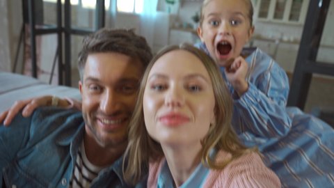 Happy family with waving hands looking at camera during video call at home