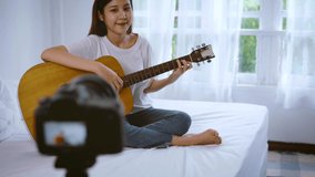 Asian woman bloggers playing guitar and singing live stream via social media. 4K