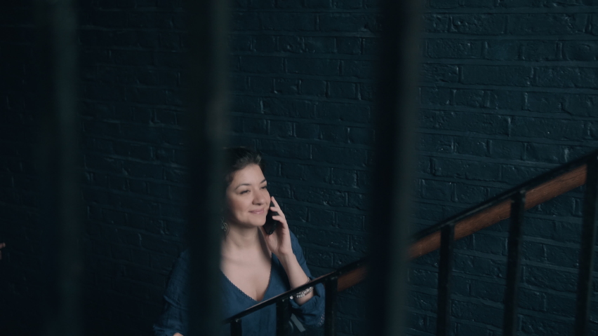 Young woman listening to the phone and walking up the stairs in the building