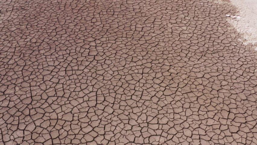 A view of a cracked surface of a parched lake. The concept of global warming, environmental pollution and post-apocalypse | Shutterstock HD Video #1064487067