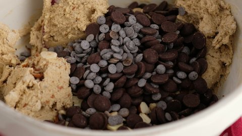 Woman making and Mixing Chocolate Chip Cookies dough in a transparent ceramic bowl in 4K. Concept of Preparing Chocolate Chip cookies step by step.